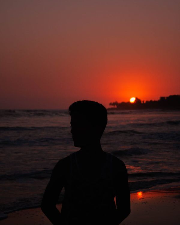 Silhouette of person meditating at sunrise with amber glow.